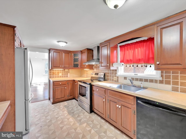 kitchen with stainless steel appliances, light countertops, a healthy amount of sunlight, a sink, and wall chimney exhaust hood