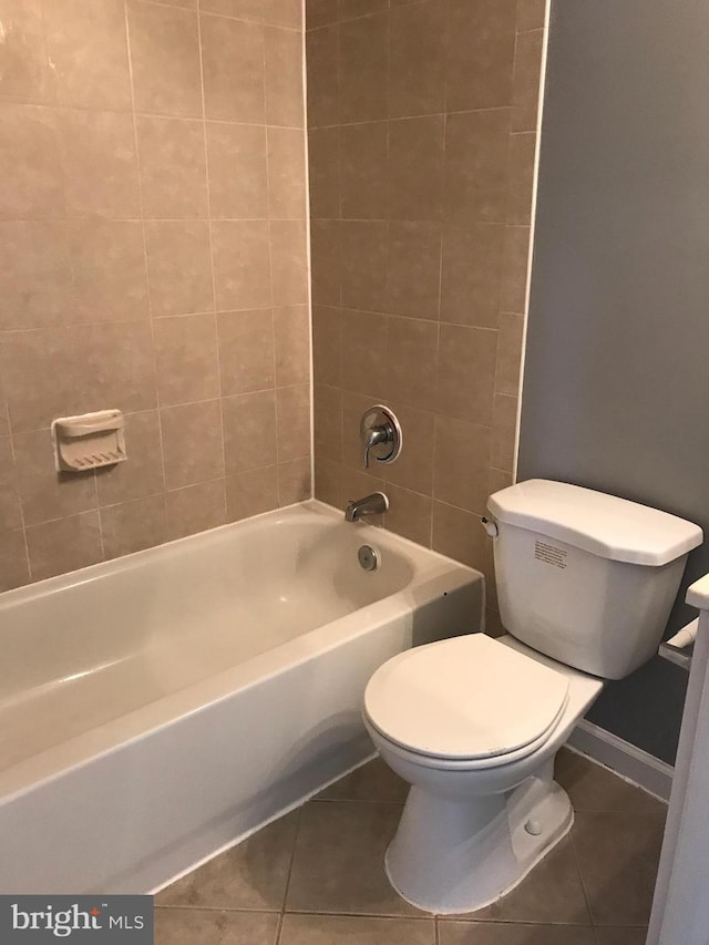 bathroom featuring washtub / shower combination, tile patterned flooring, baseboards, and toilet