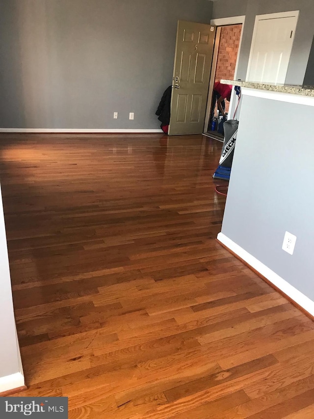 spare room featuring dark wood-style floors and baseboards