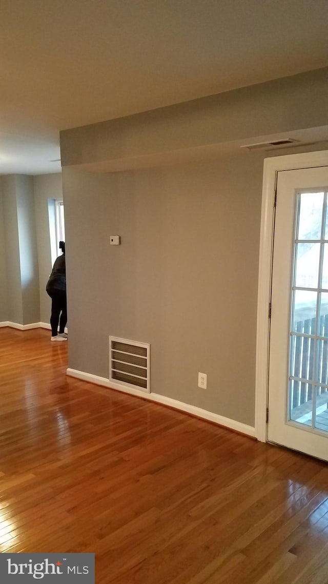 spare room with visible vents, baseboards, and wood finished floors