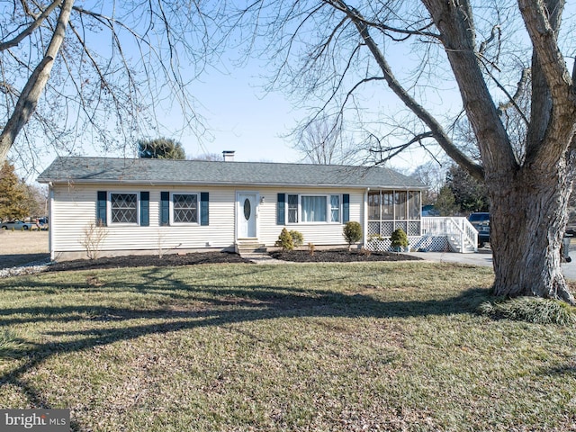 ranch-style house with entry steps, a sunroom, and a front yard