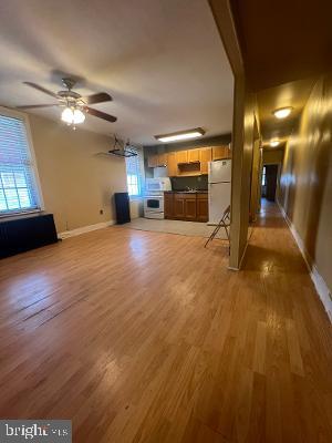 unfurnished living room with light wood finished floors, baseboards, and a ceiling fan