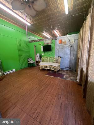 miscellaneous room featuring a baseboard heating unit, ceiling fan, wood finished floors, and an ornate ceiling