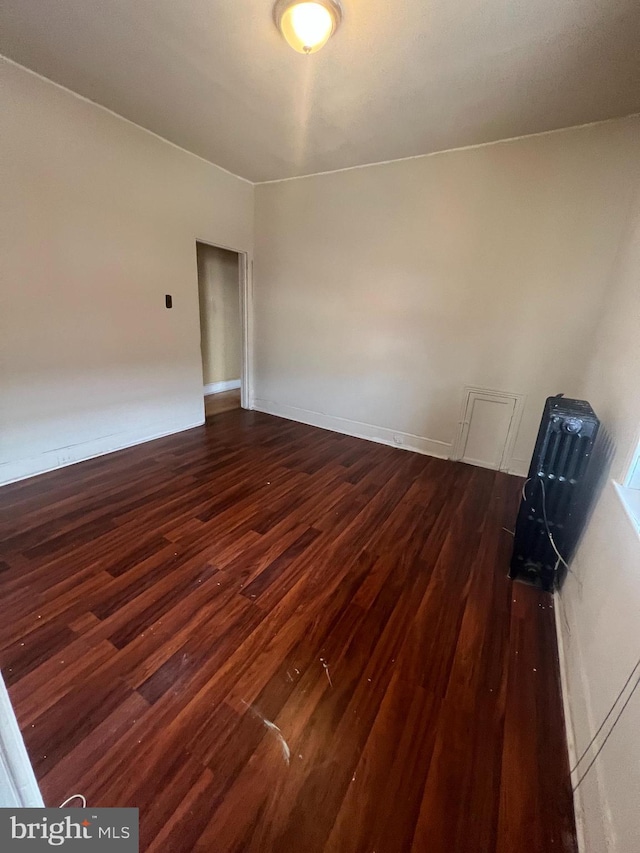 empty room featuring dark wood-style floors and baseboards