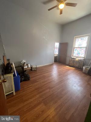 spare room featuring dark wood finished floors, radiator heating unit, and ceiling fan