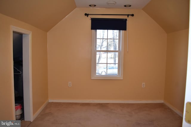 bonus room with lofted ceiling, baseboards, and light colored carpet