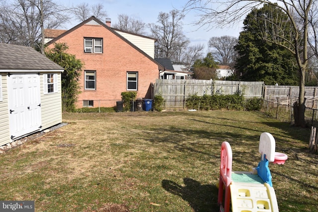 view of yard featuring fence, a storage unit, and an outbuilding