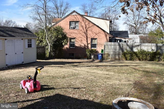 exterior space with fence, an outdoor structure, a chimney, and a lawn