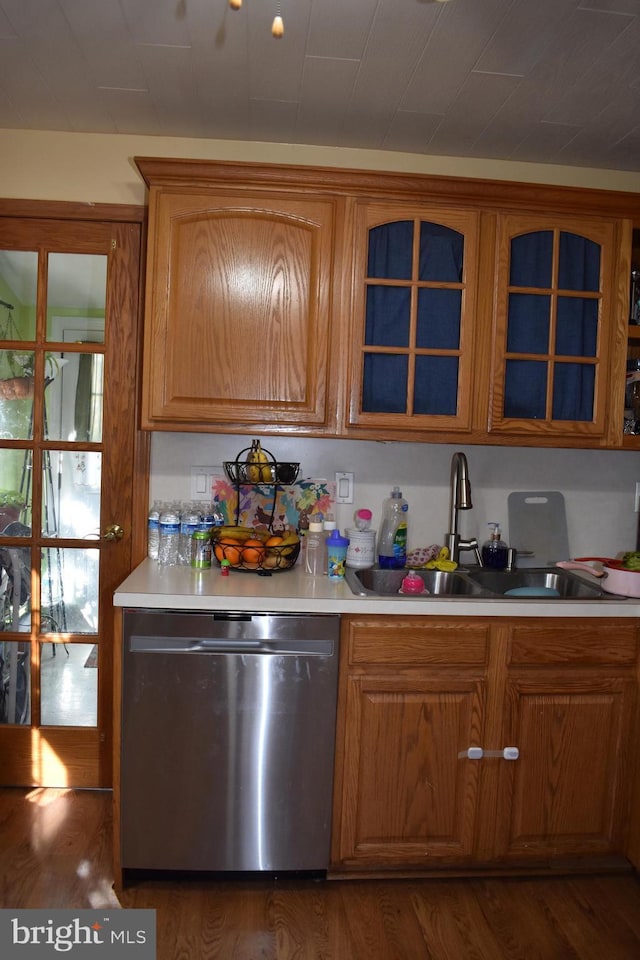 kitchen featuring dark wood finished floors, light countertops, a sink, and stainless steel dishwasher