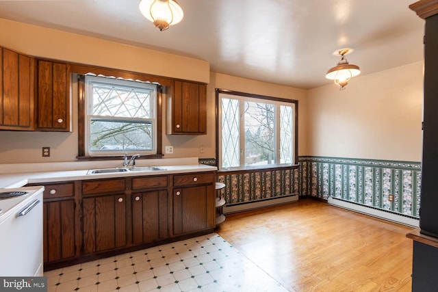 kitchen with a baseboard radiator, a sink, light countertops, baseboard heating, and light floors