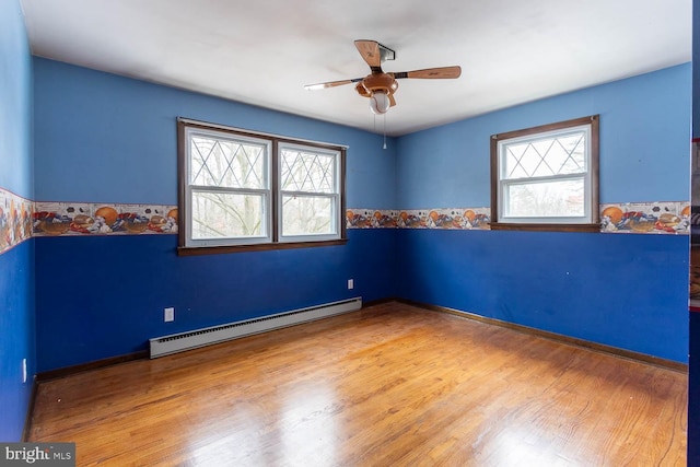 unfurnished room featuring ceiling fan, baseboard heating, and wood finished floors