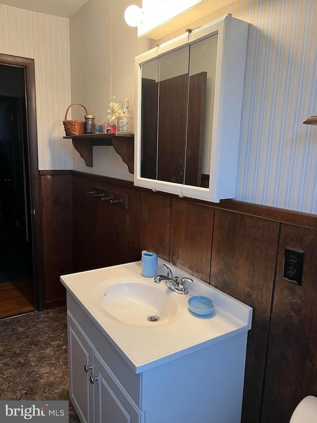 bathroom featuring a wainscoted wall, wallpapered walls, and vanity