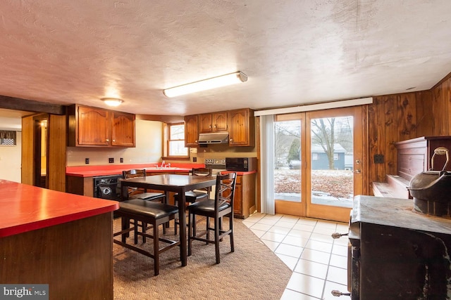 dining room featuring wood walls, a textured ceiling, and light tile patterned floors