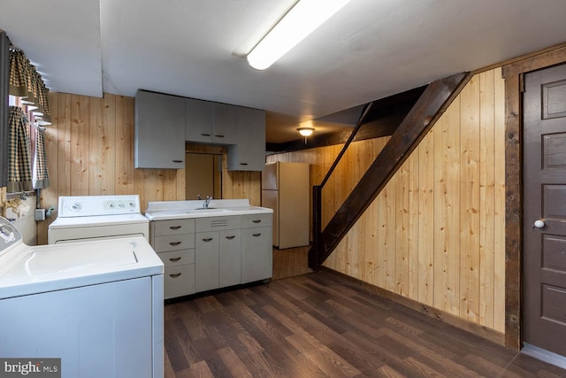 washroom featuring dark wood-style floors, separate washer and dryer, cabinet space, and wooden walls