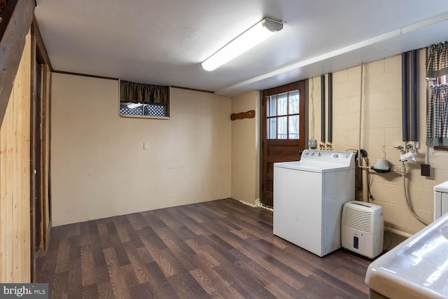 washroom featuring dark wood-type flooring, concrete block wall, laundry area, and separate washer and dryer