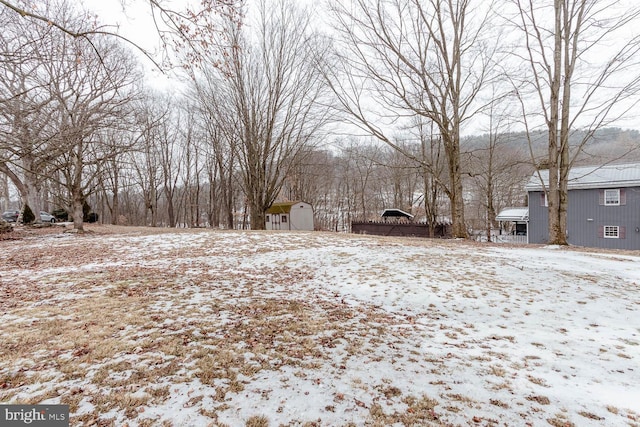 yard layered in snow with a storage unit and an outdoor structure