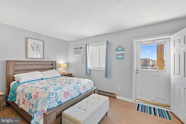 bedroom with a textured ceiling, a baseboard radiator, baseboards, and light wood-style floors