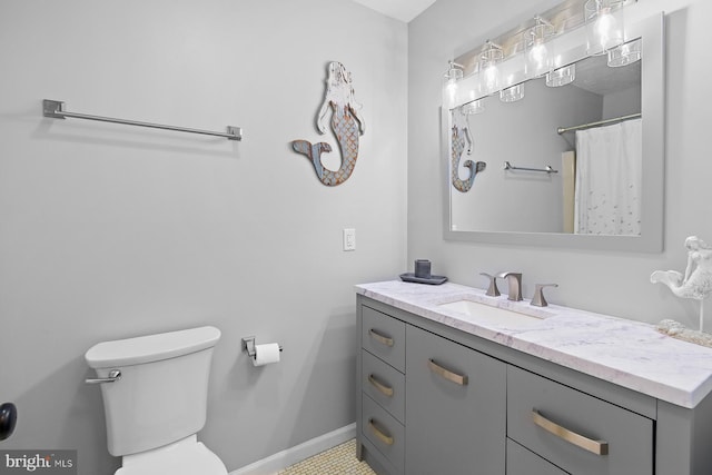 bathroom featuring baseboards, vanity, and toilet