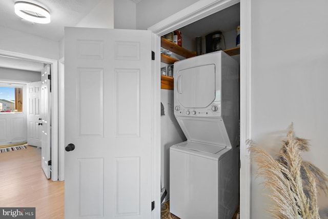 clothes washing area featuring light wood-style floors, stacked washer and clothes dryer, and laundry area