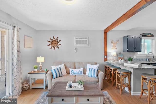 living area with light wood-style floors, a textured ceiling, and a wall mounted AC