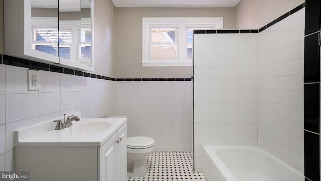 bathroom featuring a bathtub, a healthy amount of sunlight, tile walls, and toilet