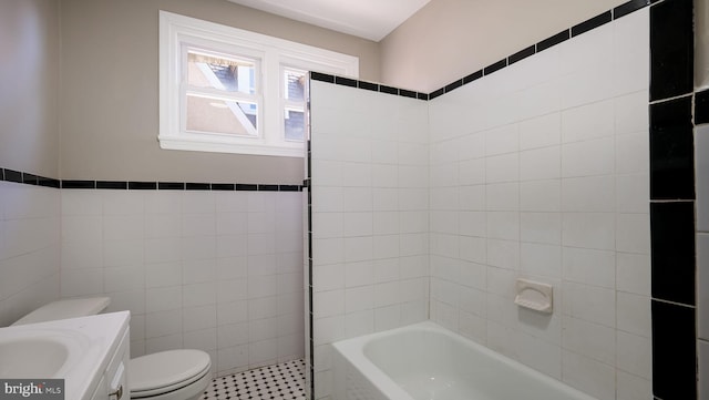 bathroom with a tub to relax in, toilet, walk in shower, vanity, and tile walls