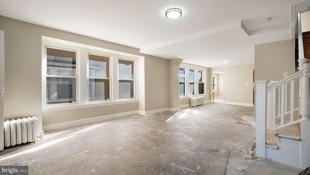 empty room with radiator, stairs, and baseboards