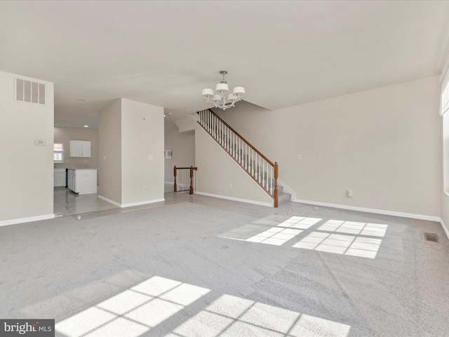 unfurnished living room featuring a chandelier, visible vents, and light colored carpet