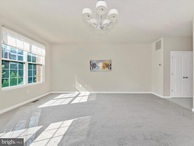 spare room featuring light colored carpet, a notable chandelier, visible vents, and baseboards