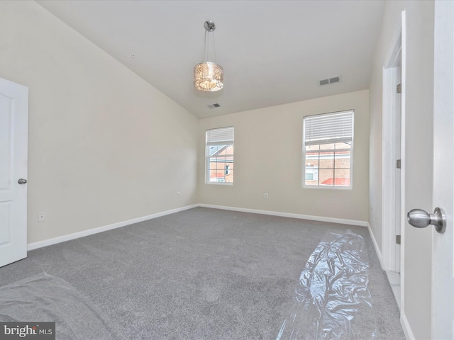 carpeted empty room with lofted ceiling, visible vents, and baseboards