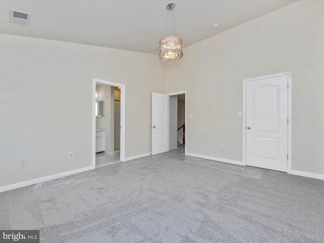 unfurnished bedroom featuring baseboards, a notable chandelier, visible vents, and light colored carpet