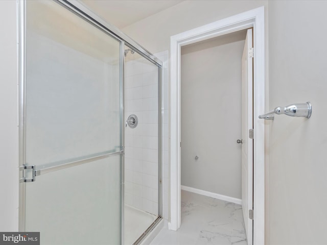 full bathroom featuring marble finish floor, a shower stall, and baseboards