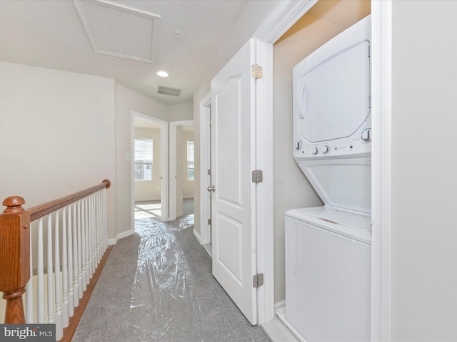 laundry room featuring laundry area, attic access, visible vents, baseboards, and stacked washer / drying machine