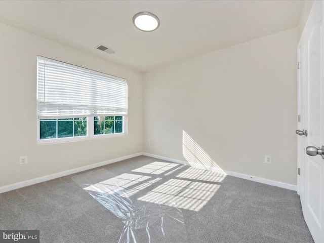 spare room featuring carpet floors, visible vents, and baseboards