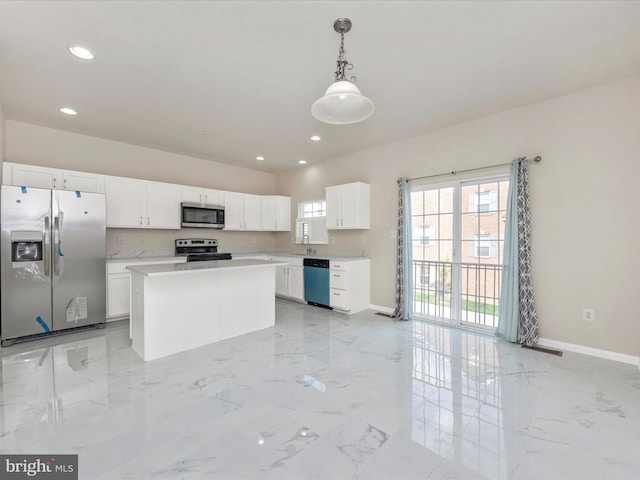 kitchen featuring white cabinets, a kitchen island, appliances with stainless steel finishes, hanging light fixtures, and light countertops