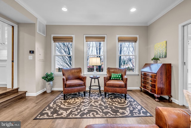 sitting room with plenty of natural light, ornamental molding, and wood finished floors