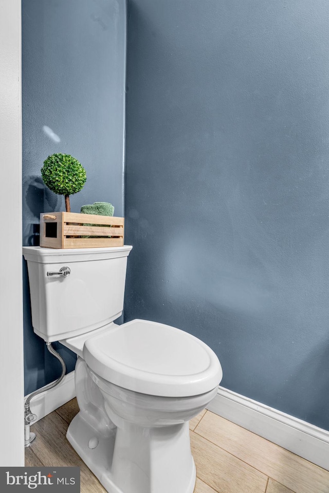 bathroom with toilet, baseboards, and wood finished floors