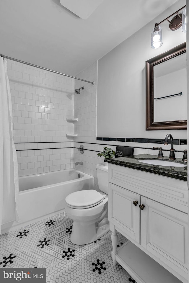 bathroom with tile walls, shower / bath combination with curtain, toilet, vanity, and tile patterned flooring