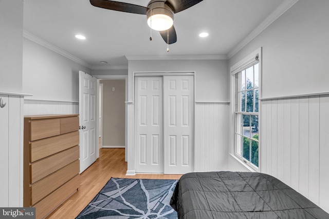 bedroom with ornamental molding, light wood finished floors, a closet, and wainscoting