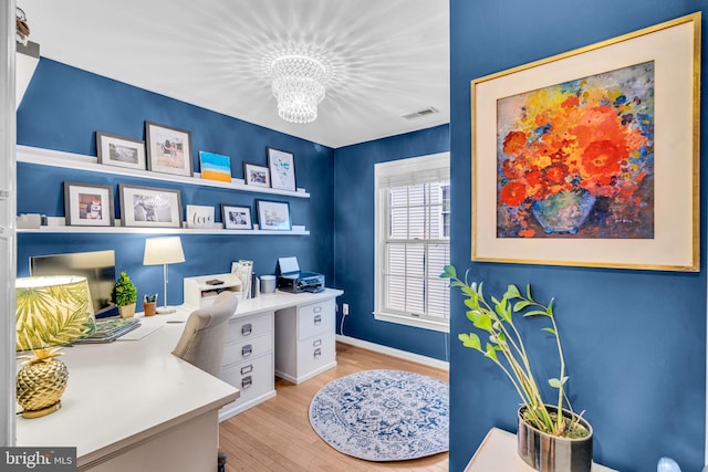 office featuring baseboards, light wood finished floors, visible vents, and an inviting chandelier