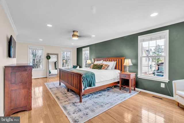 bedroom featuring light wood-type flooring, visible vents, crown molding, and baseboards