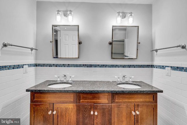 bathroom with a sink, tile walls, and double vanity