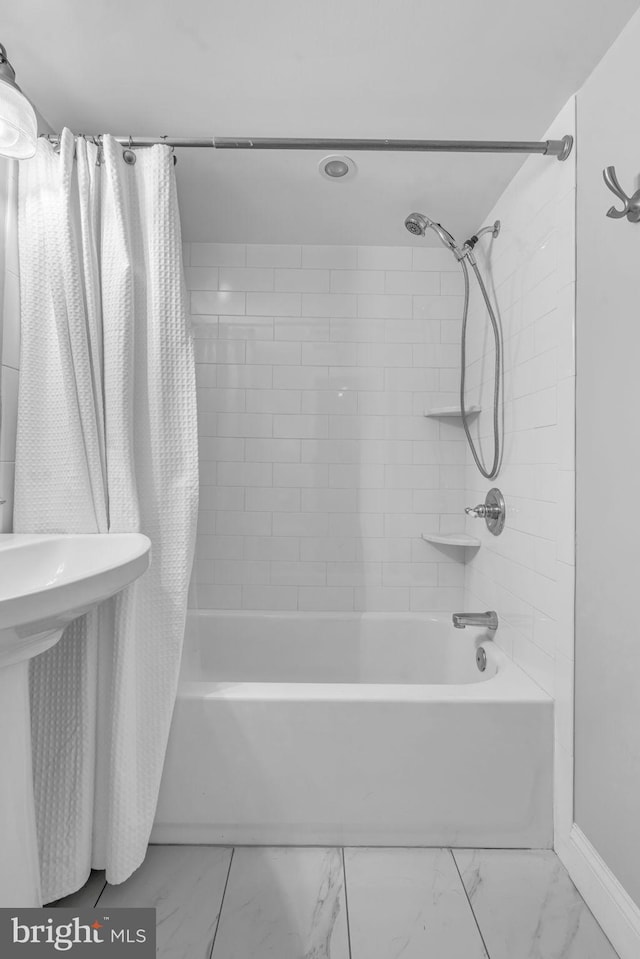 bathroom featuring shower / bath combination with curtain, marble finish floor, and baseboards