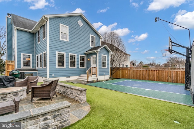 back of house with a patio area, basketball hoop, fence, and a yard