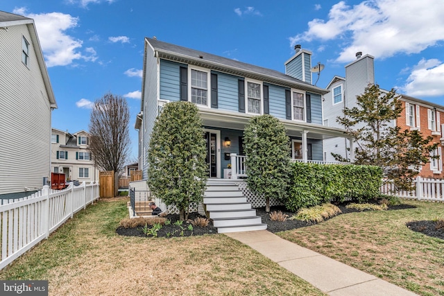 view of front of property with covered porch, a front lawn, and fence private yard