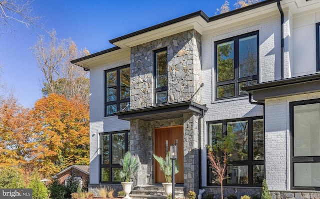 entrance to property featuring stone siding and brick siding