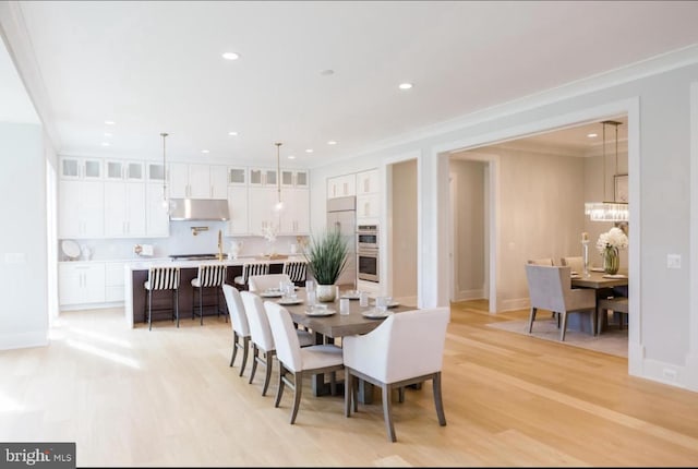 dining room with ornamental molding, light wood finished floors, and recessed lighting