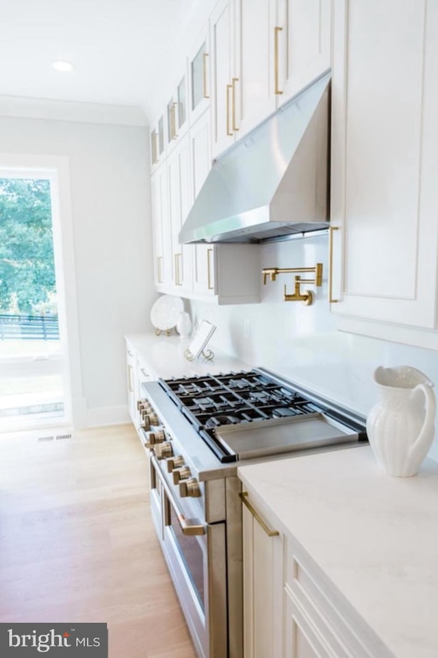 kitchen with light wood-style flooring, under cabinet range hood, white cabinetry, double oven range, and glass insert cabinets