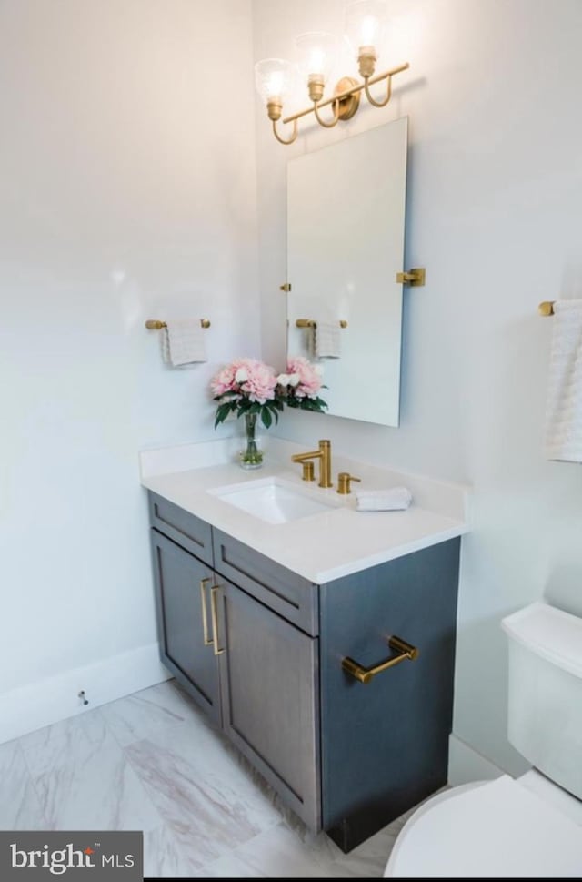 bathroom featuring baseboards, toilet, marble finish floor, an inviting chandelier, and vanity