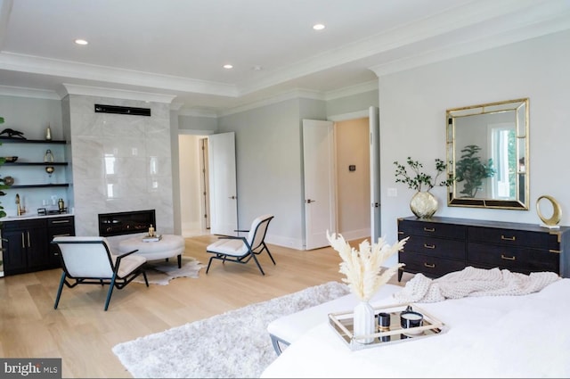 living area with light wood finished floors, a fireplace, ornamental molding, and recessed lighting